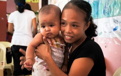 Filipino mother holding her baby during maternity leave under RA 11210