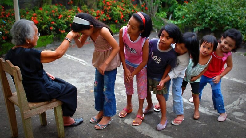 Children doing mano to an elderly Filipino woman who may receive a social pension
