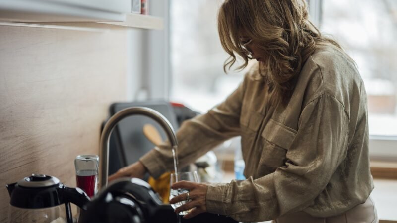 Household worker washing dishes, covered by kasambahay benefits