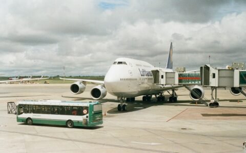 Airport apron with a shuttle bus near a parked airplane and terminal