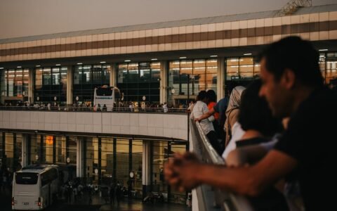 Travelers watching buses at a busy terminal near sunset