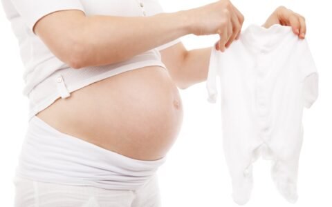 SSS maternity benefit: expectant mother holding a newborn onesie